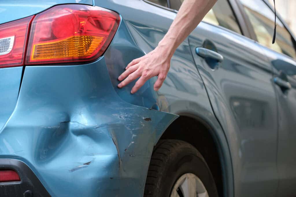 Damaged blue car rear quarter panel with dents and scratches before repair service at Symtek Automotive.