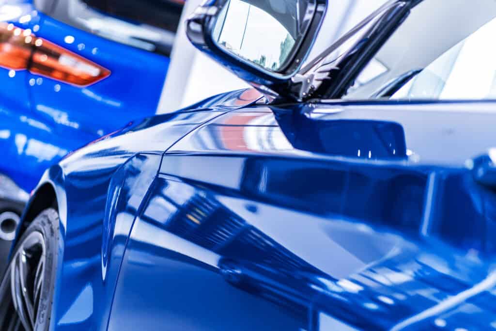 Glossy blue car side panel and mirror after paint correction and exterior detailing service at Symtek Automotive.