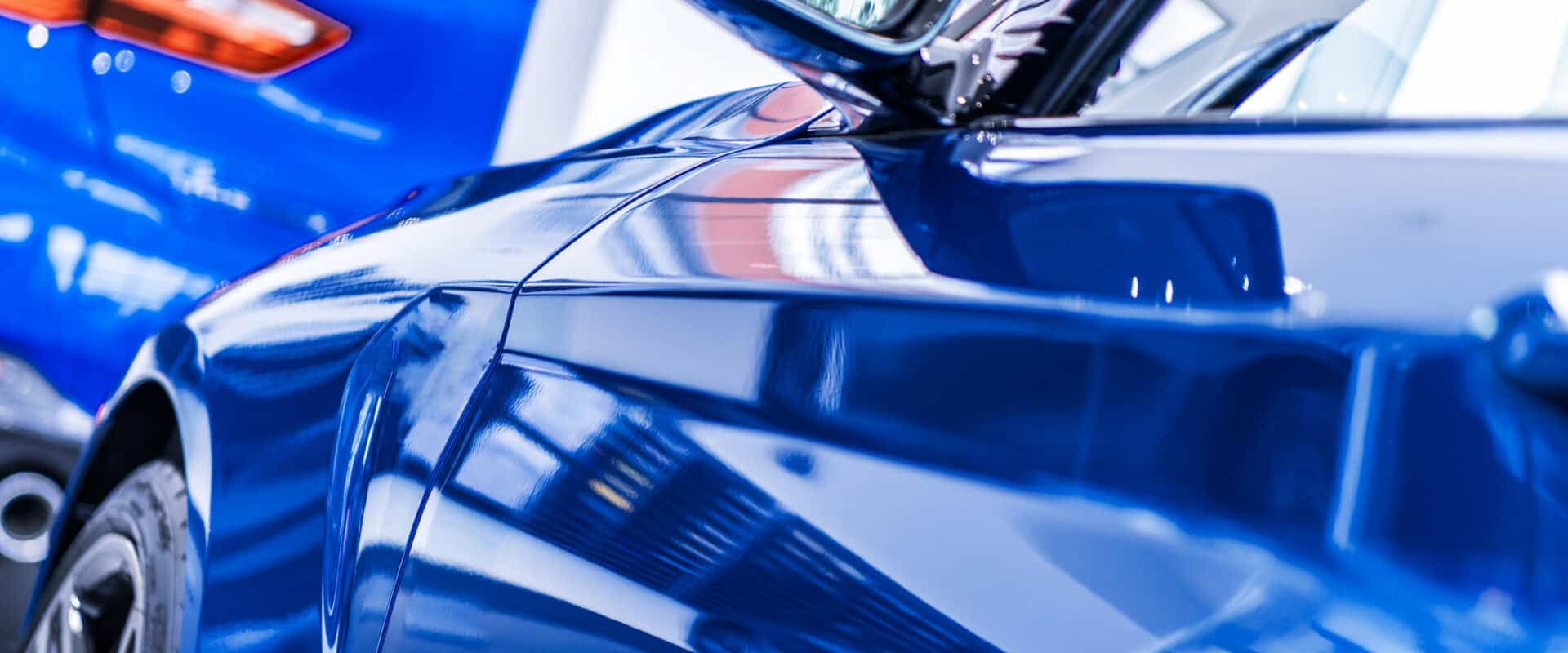 Glossy blue car side panel and mirror after paint correction and exterior detailing service at Symtek Automotive.