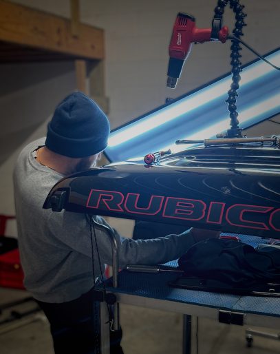 Symtek Automotive technician using paintless dent repair lighting to inspect and repair a black Jeep Rubicon in Canton, Ohio.